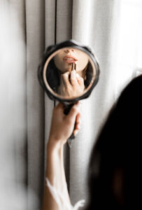 Unique Photo of Bride Holding Up Round Mirror Putting on Lipstick Getting Wedding Ready