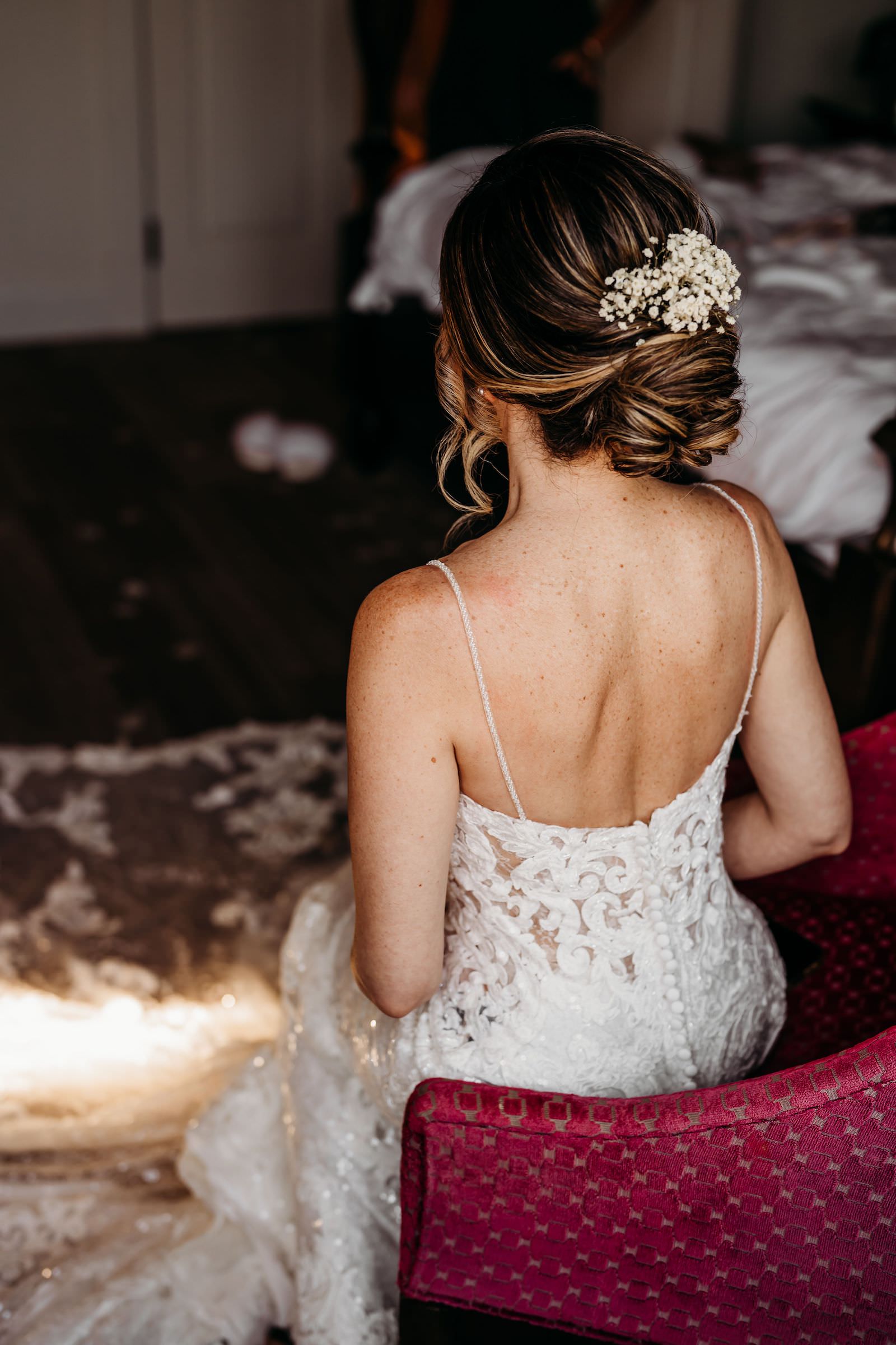 Bride Getting Wedding Ready Wearing Open Back Lace and Illusion Wedding Dress, Updo with Baby's Breath Flower Piece | Tampa Bay Wedding Hair and Makeup Adore Bridal