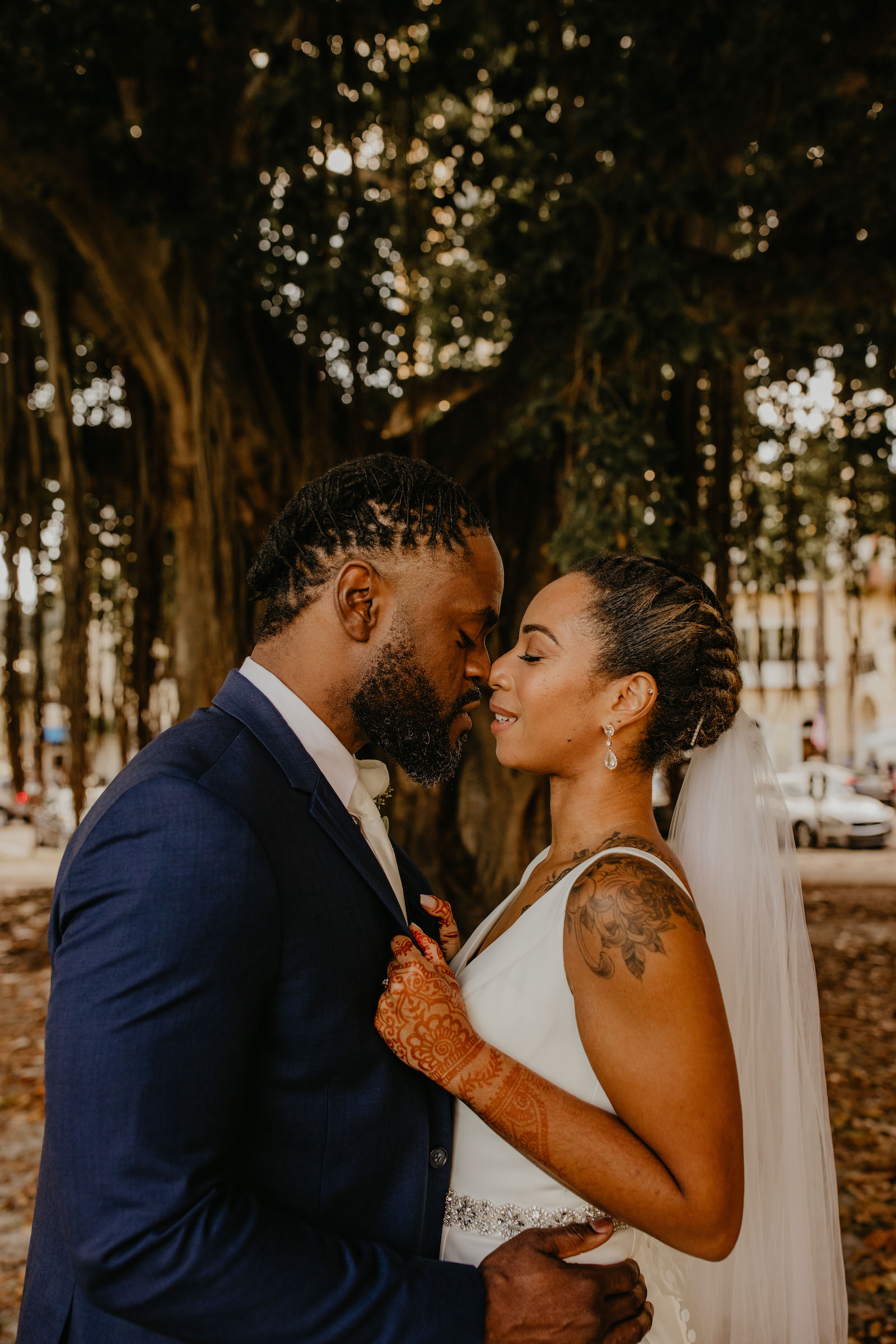 Intimate Elopement Wedding, Bride Wearing Fit and Flare Wedding Dress with Rhinestone Crystal Belt, Groom Wearing Navy Blue Suit and White Tie from Behind Under Banyon Trees, First Look Portrait