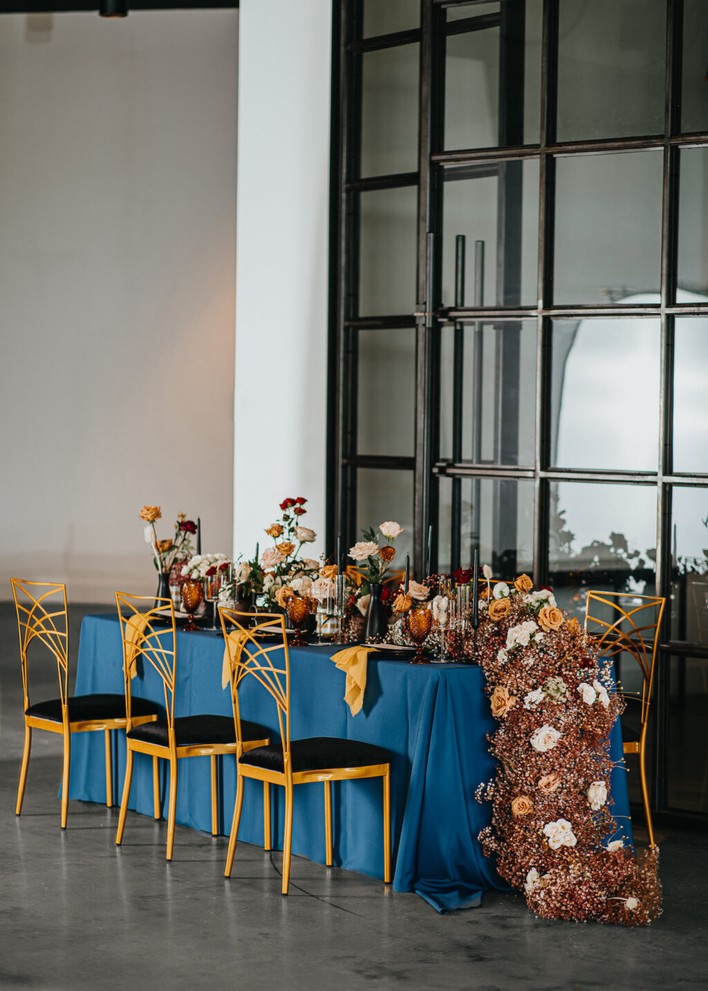 Modern and Edgy Fall Wedding Decor, Long Table with Royal Blue Table Linen, Lush Floral Table Runner, Chic Gold Chairs | Tampa Bay Wedding Venue Hyde House | Wedding Rentals Kate Ryan Event Rentals