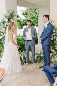 Bride and Groom Exchange Vows | Outdoor Elegant Wedding Ceremony with Gold and Floral Greenery Arch