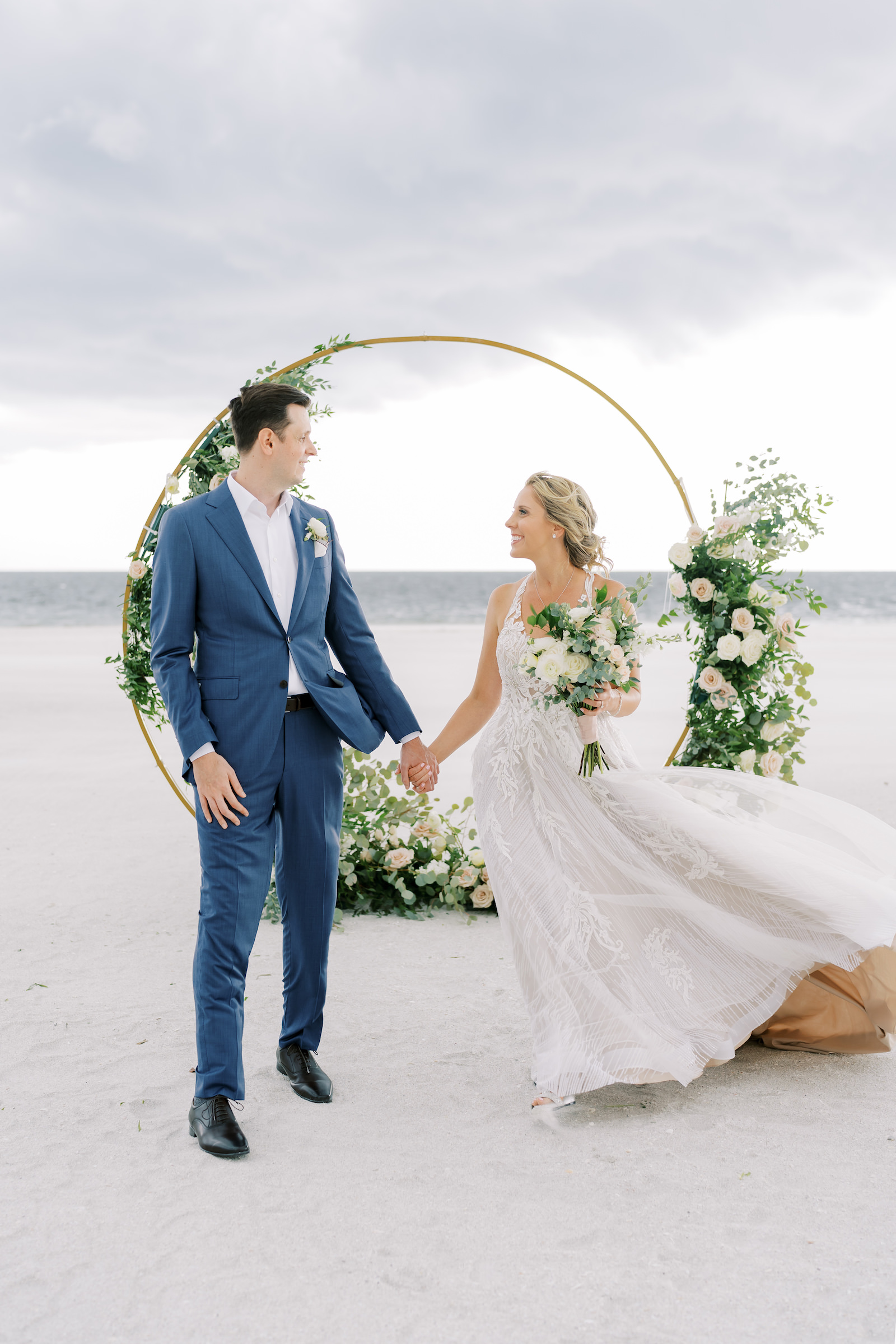 Bride and Groom Holding Hands Wedding Portrait | Outdoor Elegant Wedding Ceremony with Gold and Floral Greenery Arch