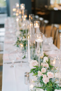Long White Candles in Glass Candle Holders with Greenery and Rose Centerpieces | Tampa Wedding Planner MDP Events