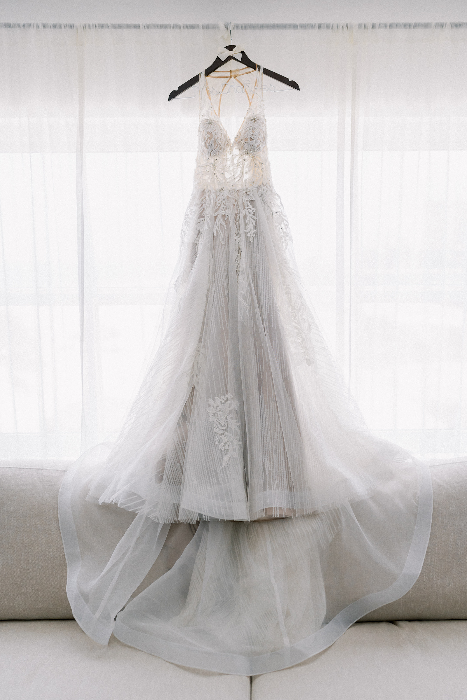 Illusion Wedding Dress with Beading Detail and Lace with Full Tulle Skirt Hanging Up Before the Wedding Portrait