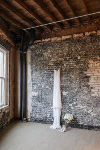 Modern and Timeless Wedding, Fitted Lace Wedding Dress Hanging on Brick Wall | Tampa Bay Wedding Photographer Lifelong Photography Studio | Wedding Venue Oxford Exchange