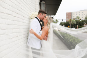 Modern and Timeless Black and White Wedding, Bride and Groom Kissing Veil Blowing in Wind Outside Wedding Venue Oxford Exchange | Tampa Bay Wedding Photographer Lifelong Photography Studio