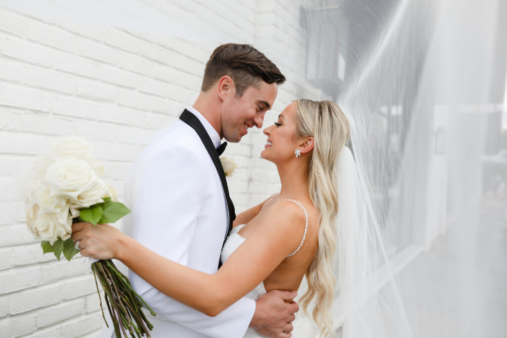 Modern and Timeless Black and White Wedding, Bride and Groom Kissing Veil Blowing in Wind Outside Wedding Venue Oxford Exchange | Tampa Bay Wedding Photographer Lifelong Photography Studio
