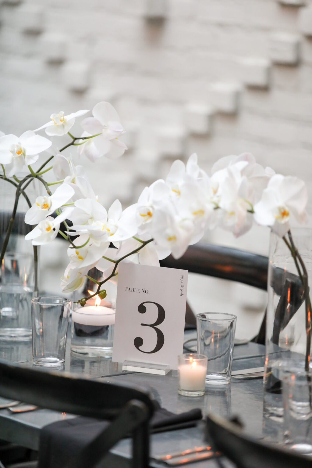 Modern Timeless Black and White Wedding Reception Decor, Black Tables and Chairs, White Orchid Floral Arrangement Centerpieces, Candlesticks in Hurricane Glass Vases | Tampa Wedding Venue Oxford Exchange | Wedding Photographer Lifelong Photography Studio