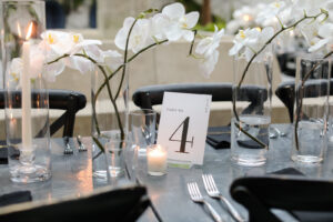 Modern Timeless Black and White Wedding Reception Decor, Black Tables and Chairs, White Orchid Floral Arrangement Centerpieces, Candlesticks in Hurricane Glass Vases | Tampa Wedding Venue Oxford Exchange | Wedding Photographer Lifelong Photography Studio