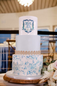 Three Tier Round White and Blue Nautical Coastal Wedding Cake with Monogram and Hand Painted Flowers