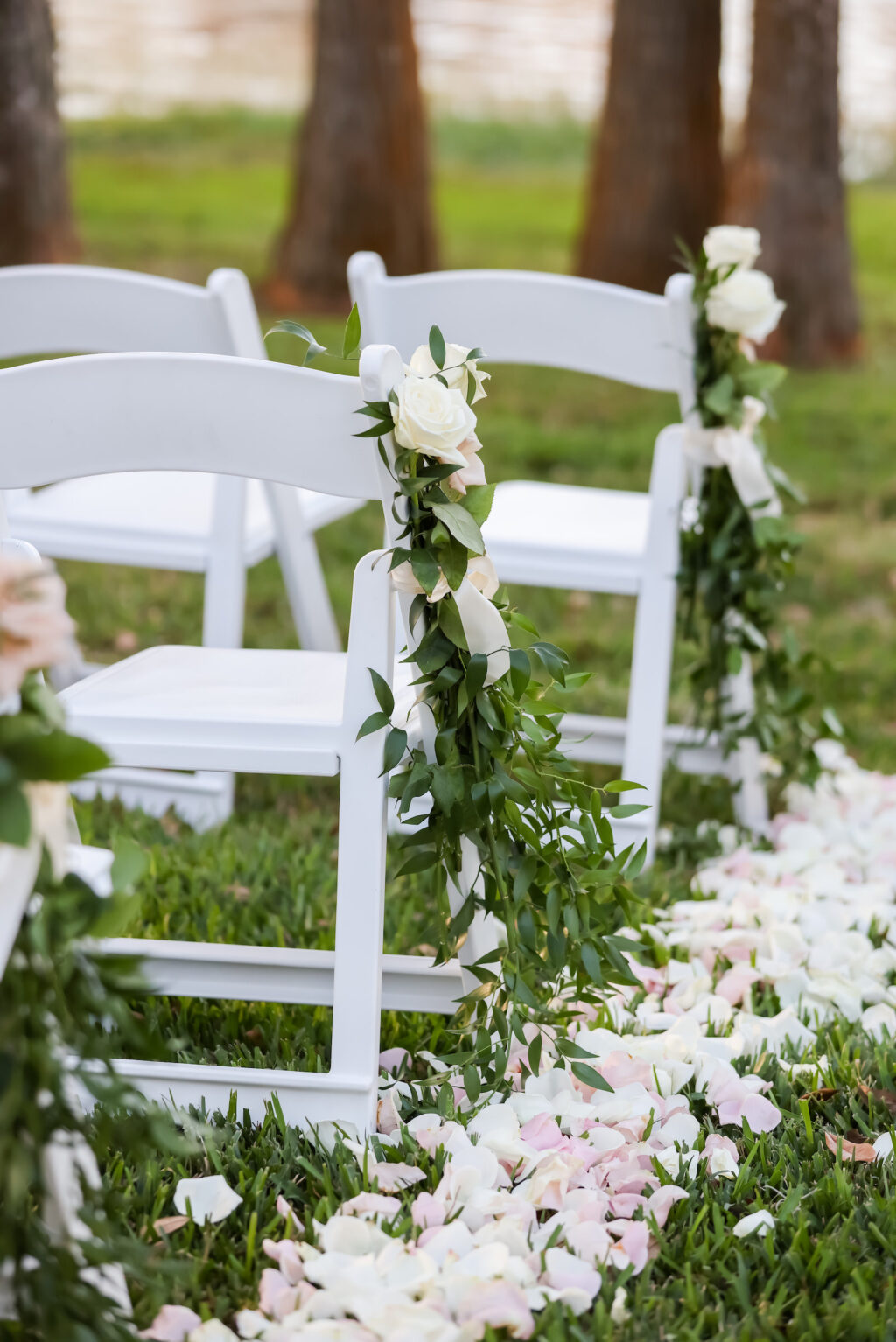 Romantic Classic Outdoor Wedding Ceremony Decor, White Folding Garden Chairs, Greenery and White Roses Arrangement on Chairs, Rose Petals | Tampa Bay Wedding Photographer Lifelong Photography Studio | Wedding Planner Special Moments Event Planning | Wedding Rentals Kate Ryan Event Rentals