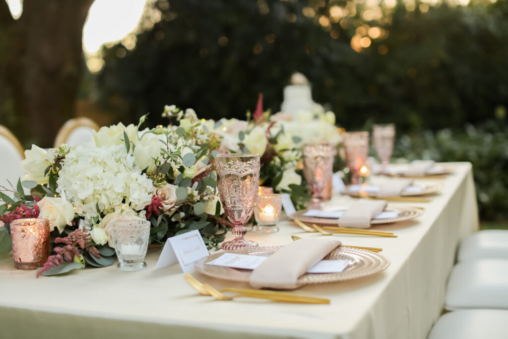 Romantic Pink Wedding Reception Decor, Long Table with Ivory Linen, Gold Silverware, Vintage Pink Glassware, White Hydrangeas, Greenery Eucalyptus, and Pink Floral Garland | Tampa Bay Wedding Photographer Lifelong Photography Studio | Wedding Planner Special Moments Event Planning | Wedding Rentals Kate Ryan Event Rentals |