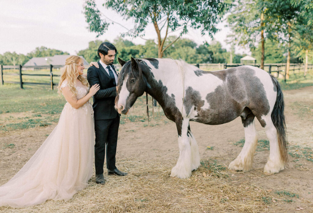 Bride Wearing Boho Off White Flowy Lace High Neck Wedding Dress and Groom Petting Brown and White Horse | Rustic Tampa Bay Wedding Venue Mill Pond Estate