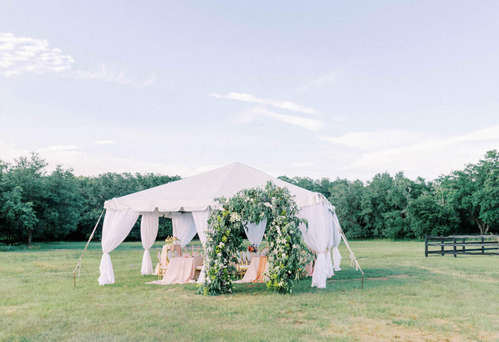 Garden Whimsical Wedding Decor, White Linen Tent, Greenery Arch with White Flowers At Outdoor Tampa Bay Wedding Venue Mill Pond Estate