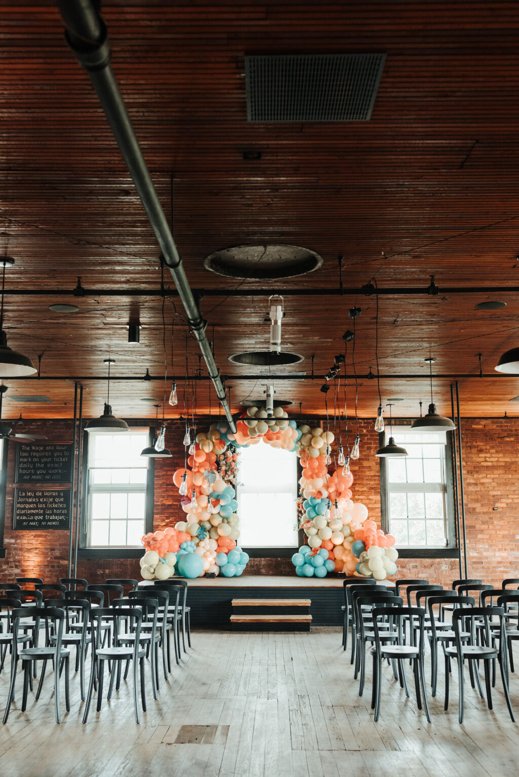 Industrial Indoor Wedding Ceremony with Balloon Arch Décor and Modern Black Chairs | JC Newman Cigar Factory Ybor Historic Wedding Venue