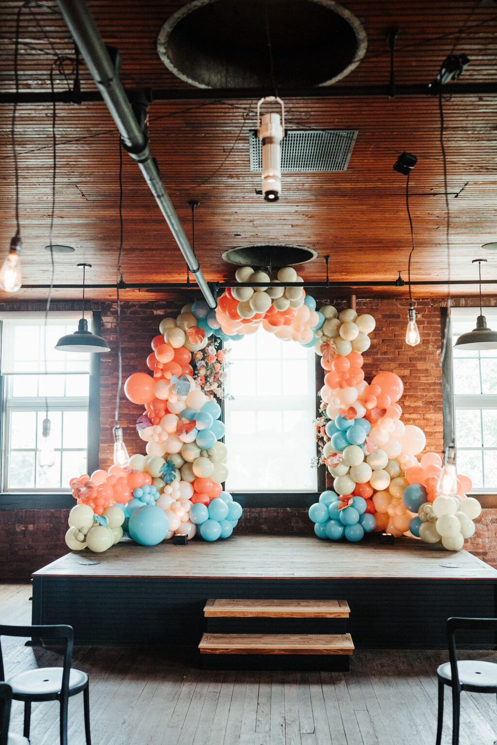 Industrial Indoor Wedding Ceremony with Balloon Arch Décor and Modern Black Chairs | JC Newman Cigar Factory Ybor Historic Wedding Venue