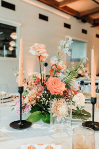 Coral and Peach Flowers with Greenery Wedding Centerpieces with Tall Candles with Black Candle Stick Wedding Reception Décor Ideas