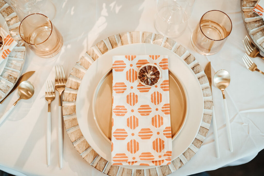 White and Gold Chargers with Patterned Orange Napkins