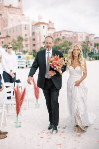 Vibrant Boho Beach Wedding Ceremony, Bride Holding Hot Pink Floral Wedding Bouquet Walking Down the Aisle Processional Photo | St. Petersburg Waterfront Historic Wedding Venue The Don CeSar | Tampa Bay Wedding Hair and Makeup Femme Akoi Beauty Studio