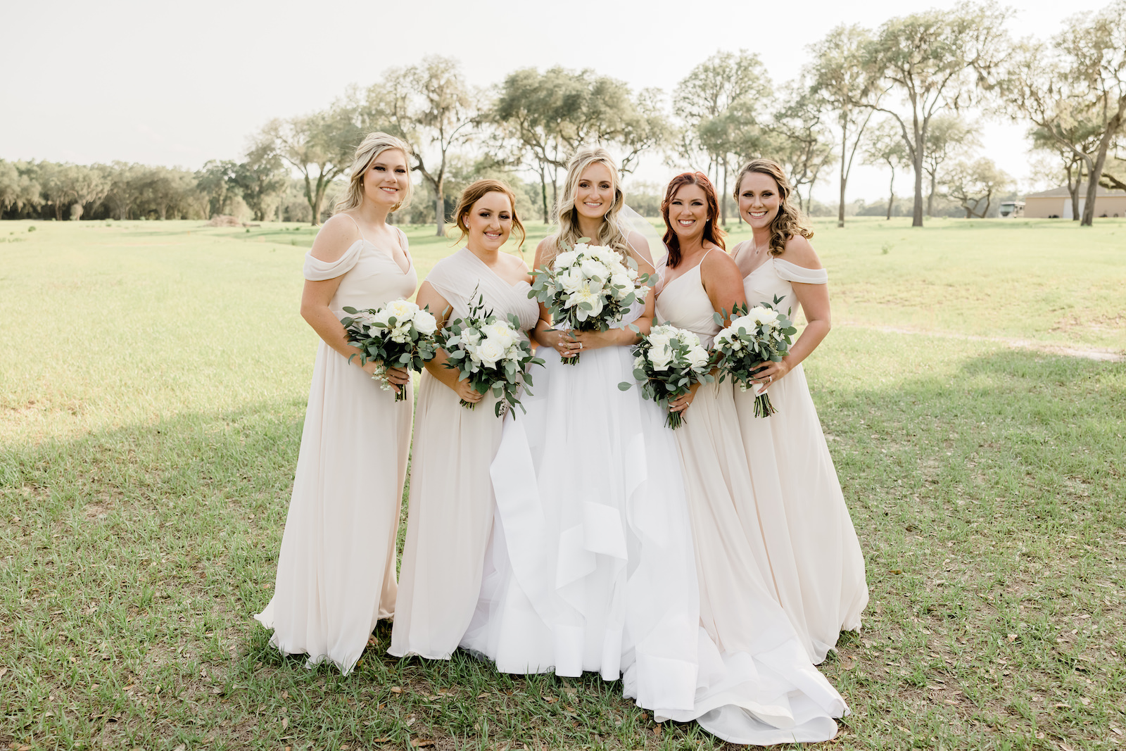 Tampa Bay and Bridesmaids Wearing Mix and Match Champagne/Ivory Dresses Holding Classic White and Greenery Floral Bouquets