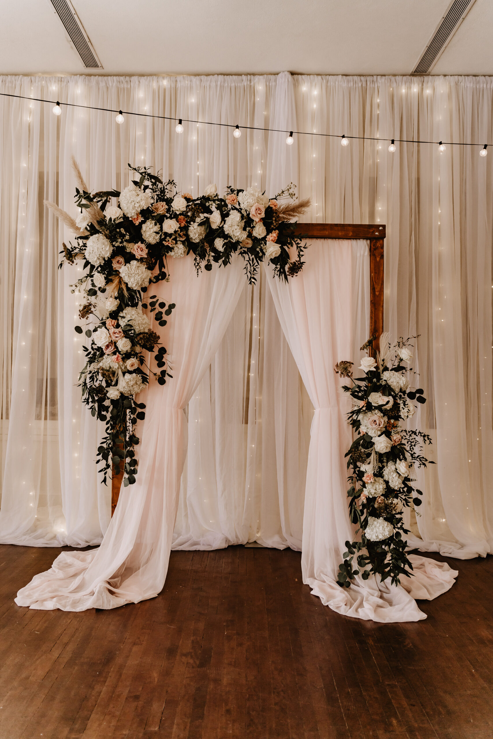Neutral Boho Modern Wedding Ceremony Decor, Wooden Arch with White Linen Draping, Lush White Hydrangeas, Blush Pink Roses, Greenery, Pampas Grass Floral Arrangements | Tampa Bay Wedding Planner Taylored Affairs | Wedding Rentals Gabro Event Services