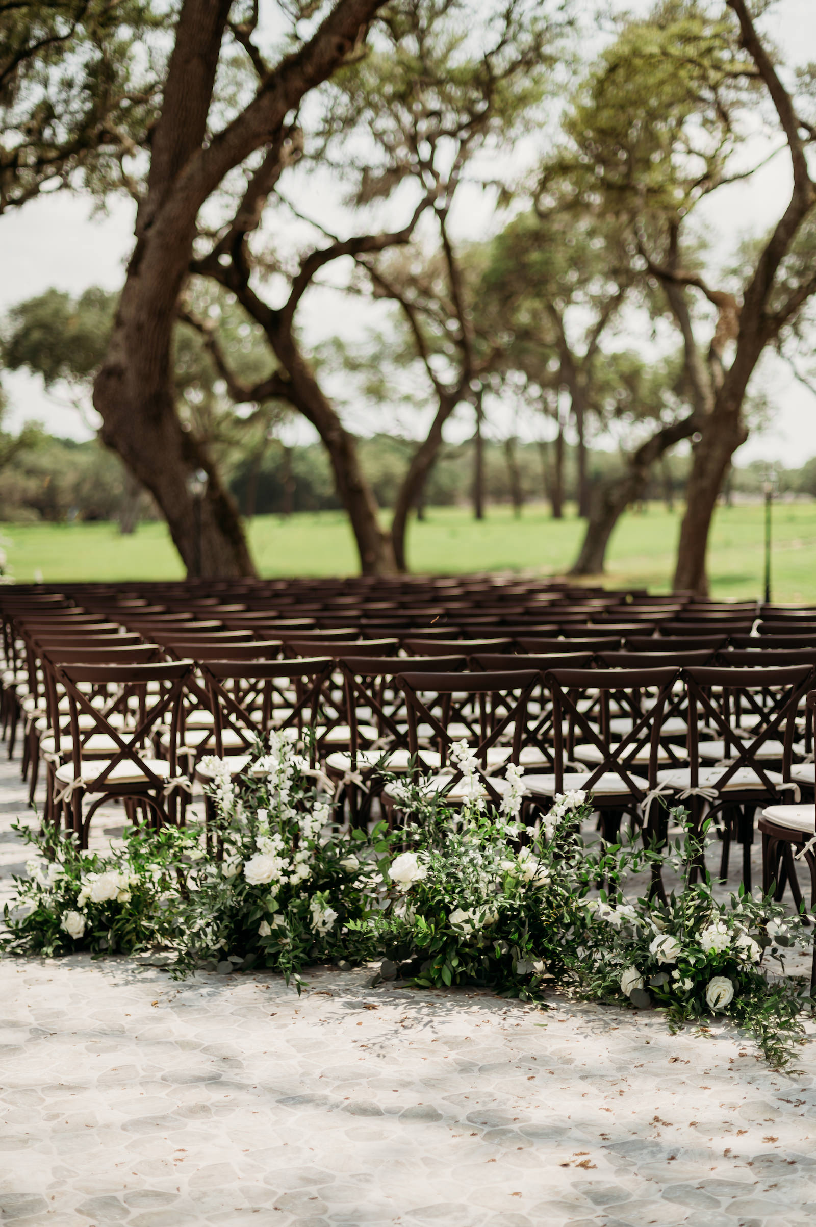 Classic Outdoor Wedding Reception Decor, Dark Wooden Cross Back Chairs, Lush Greenery and White Floral Arrangements