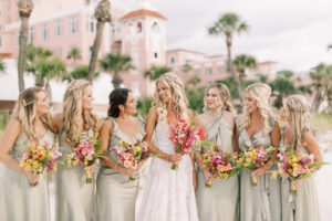 Vibrant Boho Wedding, Bride with Bridesmaids Wearing Mix and Match Sage Green Dresses Holding Hot Pink and Yellow Floral Bouquets | Tampa Bay Wedding Hair and Makeup Femme Akoi Beauty Studio | St. Petersburg Waterfront Wedding Venue The Don CeSar