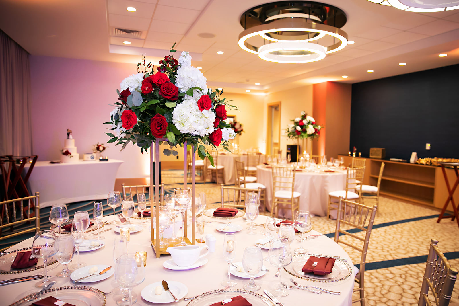 Indoor Hotel Wedding Reception with White Linens and Gold Chairs with Rose Centerpieces | Florida Wedding Venue Wyndham Grand Clearwater Beach | Florida Wedding Rentals Gabro Event Rental Services | Save the Date Florida Wedding Florist