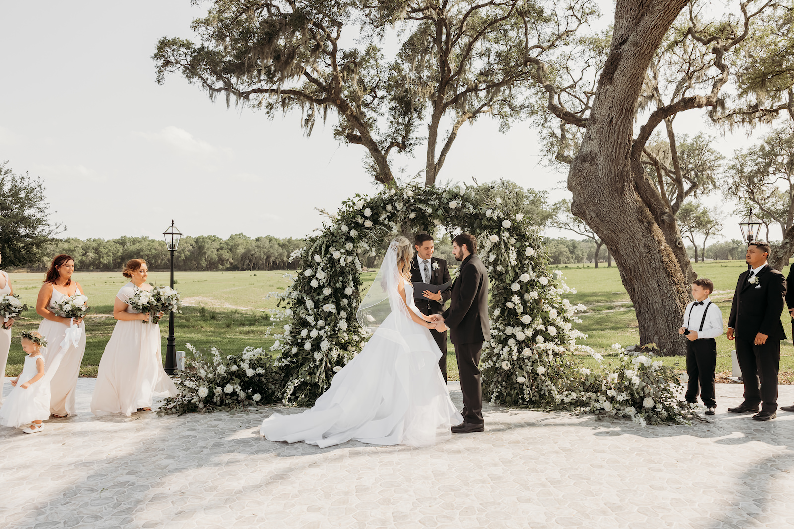 Bride and Groom Exchanging Wedding Vows, Classic Outdoor Wedding Ceremony Decor, Greenery and White Floral Arch | Tampa Wedding Venue Simpson Lakes