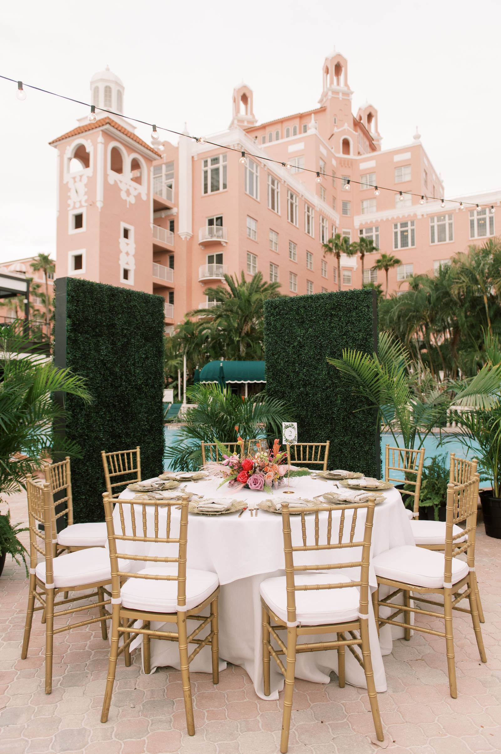 Vibrant Boho Wedding Reception Decor, White Linen Round Tables, Gold Chargers and Flatware, Low Hot Pink, Yellow and Greenery Floral Centerpiece, Greenery Hedge Walls, Hanging String Lights | St. Petersburg Waterfront Historic Wedding Venue The Don CeSar