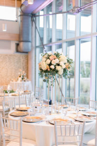 Tall Blush and White Floral and Greenery Centerpiece on Round Table with White Linen and White Chairs | Tampa Rentals Kate Ryan Event Rentals | Caterer Elite Events Catering