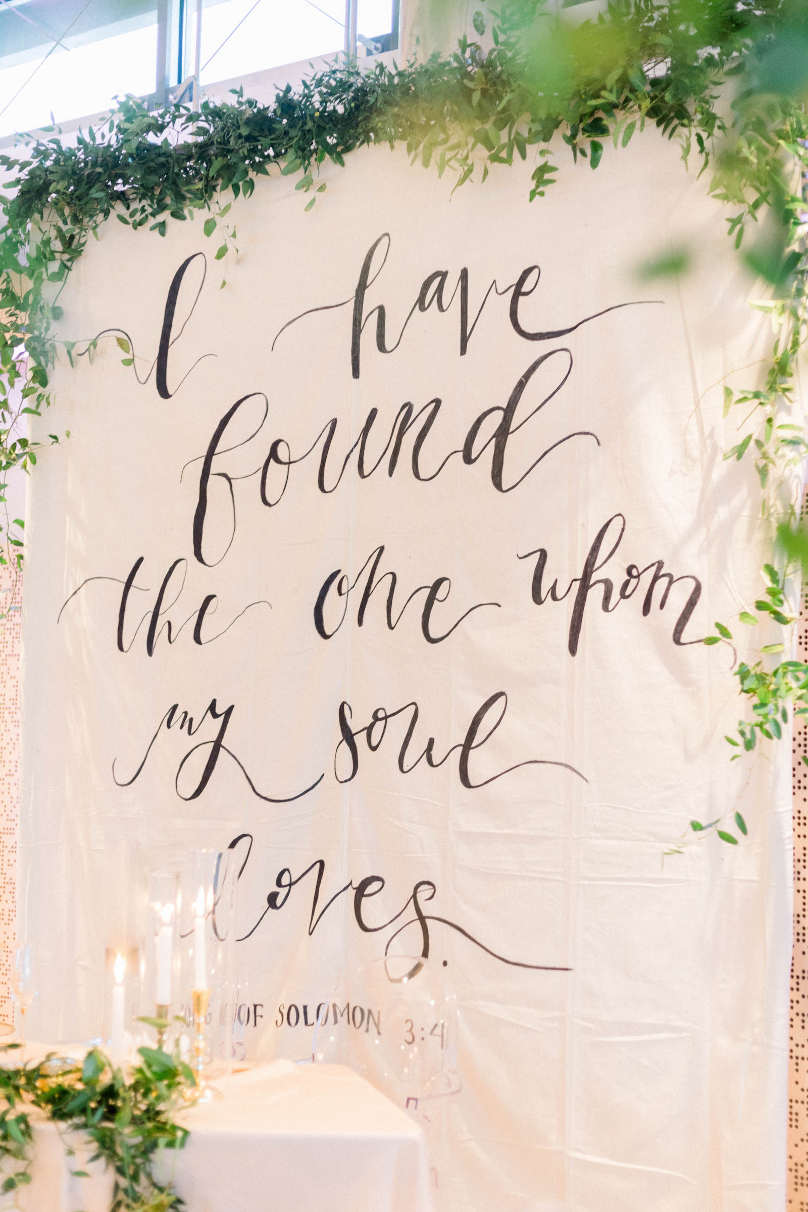 Wedding Quote Backdrop Behind Sweetheart Table in White and Greenery