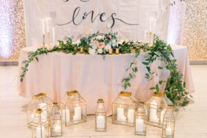 Gold Candle Lantern Wedding Décor in Front of Sweetheart Table | Kate Ryan Event Rentals
