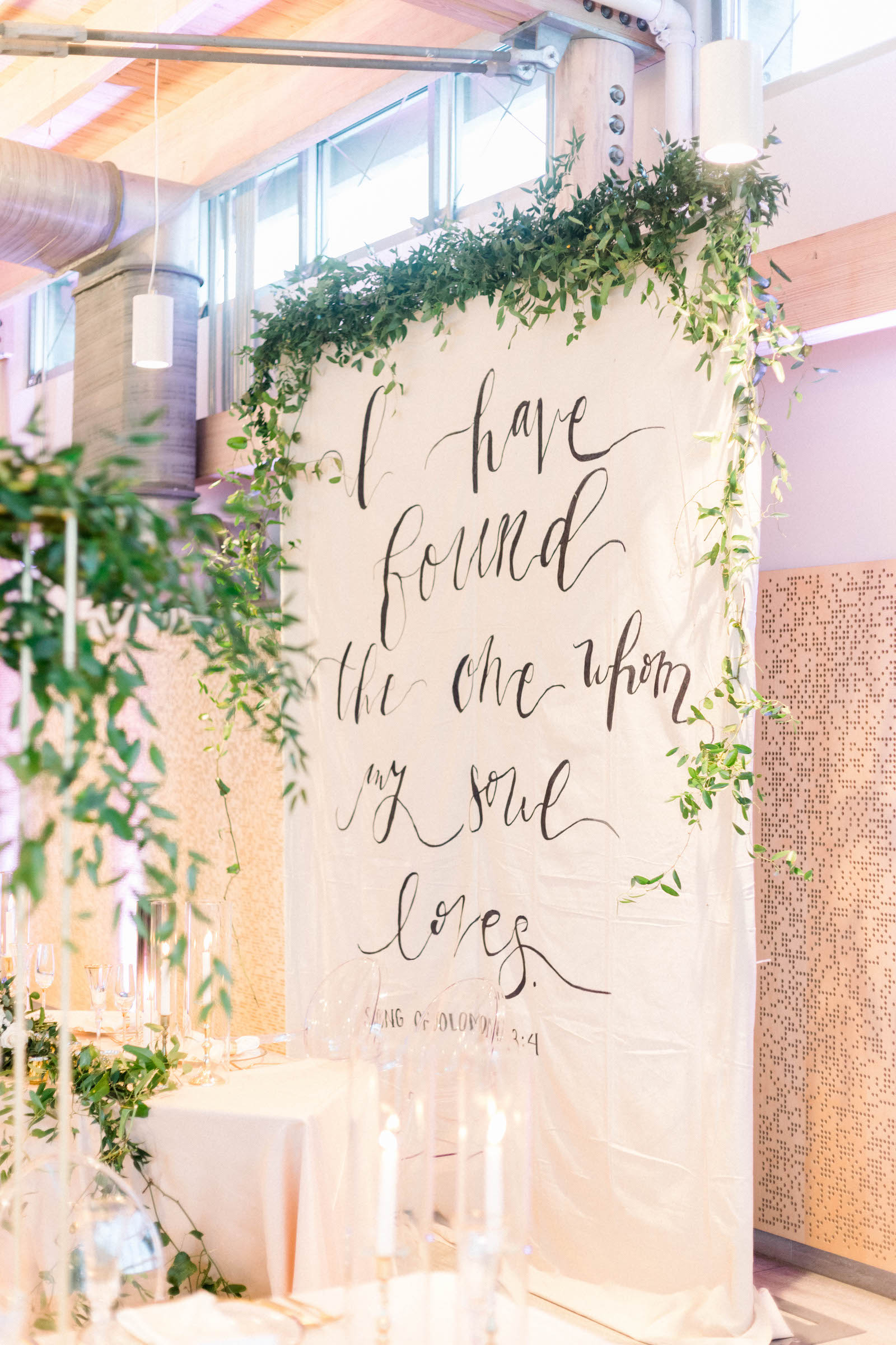 Wedding Quote Backdrop Behind Sweetheart Table in White and Greenery | Kate Ryan Event Rentals