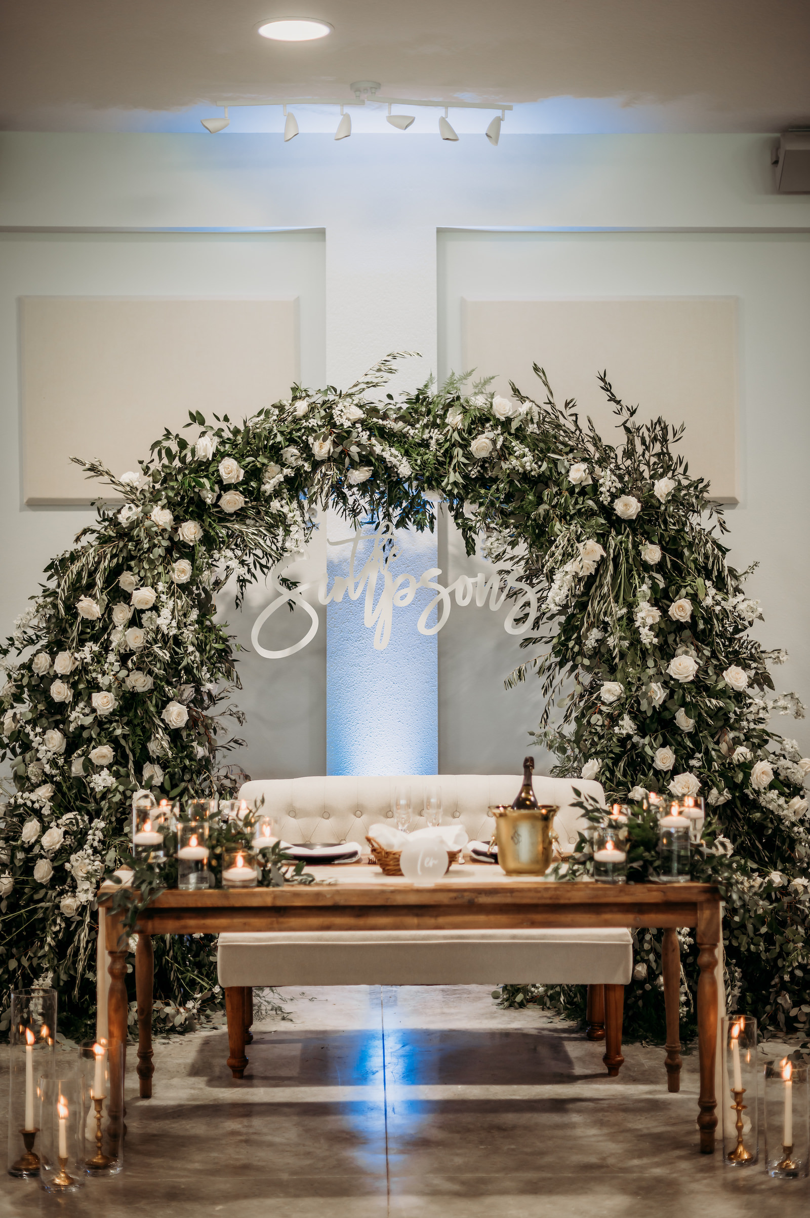 Classic Wedding Reception Decor, Long Wooden Sweetheart Table, Ivory Tufted Loveseat, Lush White Roses and Greenery Floral Arch, Custom Neon Sign