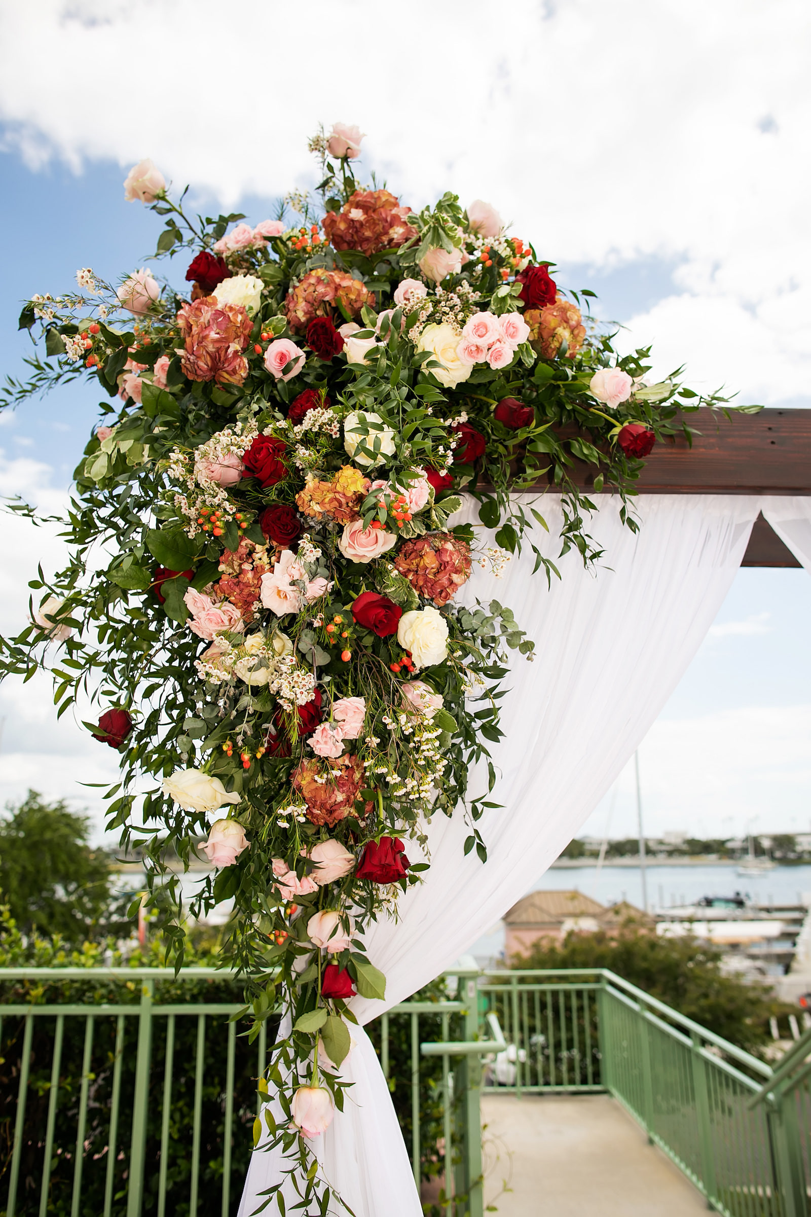 Elegant Garden Wedding Ceremony Decor, Wooden Arch with Lush Burgundy and Pink Floral Arrangements and White Linen Draping | Tampa Bay Wedding Photographer Limelight Photography | Planner Breezin Weddings | Florist Lemon Drops | Rentals Outside the Box Event Rentals