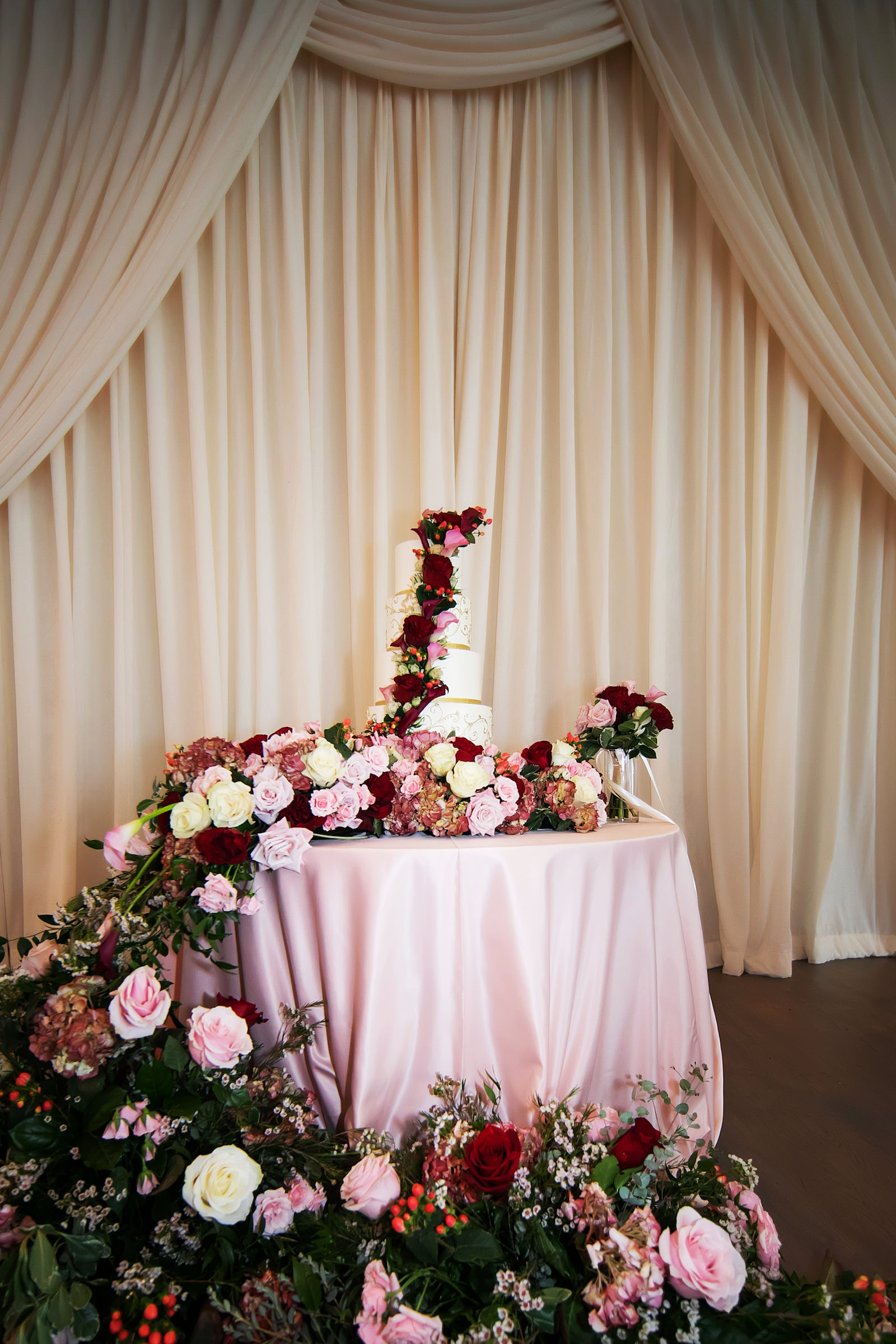 Lush Burgundy, Pink and White Roses and Greenery Floral Cascading Cake Table with 4-Tier White and Gold Wedding Cake for Garden Inspired Ballroom Wedding | Tampa Bay Photographer Limelight Photography | Florist Lemon Drops | Planner Breezin Weddings