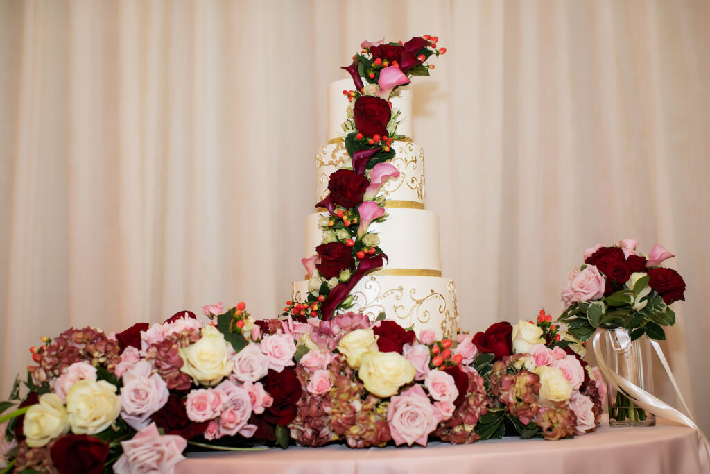 Lush Burgundy, Pink and White Roses and Greenery Floral Cascading Cake Table with 4-Tier White and Gold Wedding Cake for Garden Inspired Ballroom Wedding | Tampa Bay Photographer Limelight Photography | Florist Lemon Drops | Planner Breezin Weddings