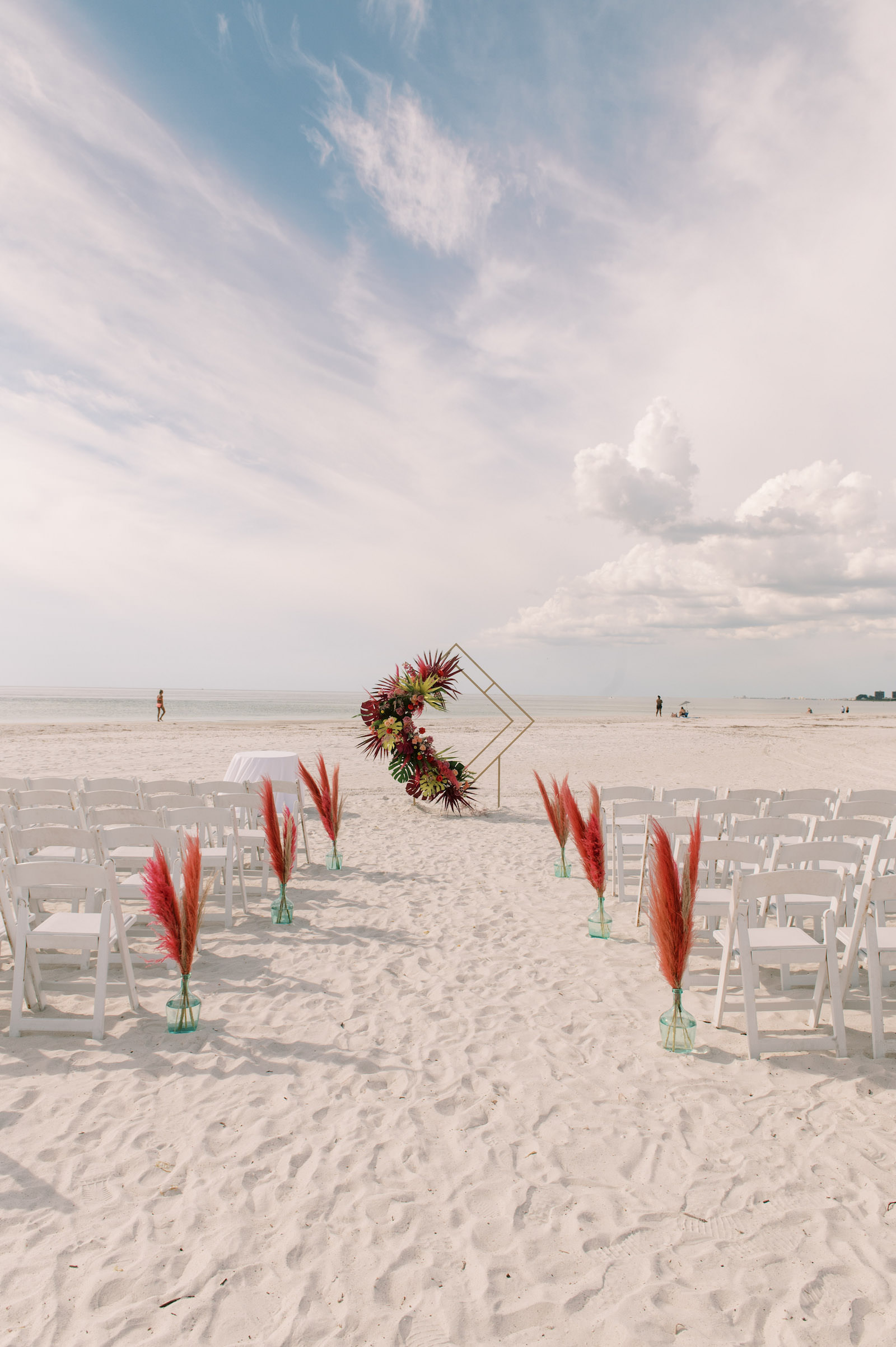 Vibrant Boho Beach Wedding, Red Pampas Grass in Vases Lining the Wedding Ceremony Aisle, Geometric Diamond Shaped Arch with Tropical Floral Arrangements | St. Pete Beach Wedding Venue The Don CeSar