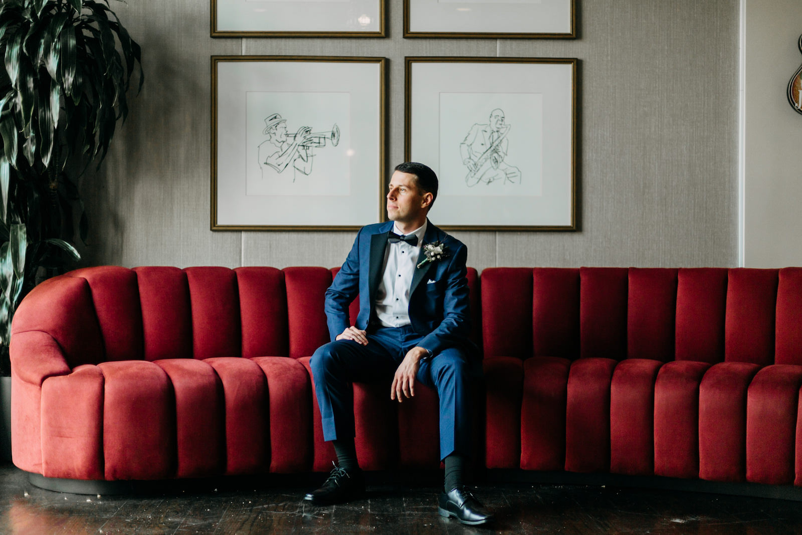 Florida Groom Wearing Midnight Blue Tuxedo Sitting on Red Tufted Velvet Couch Wedding Portrait | Tampa Bay Wedding Photographer Amber McWhorter Photography