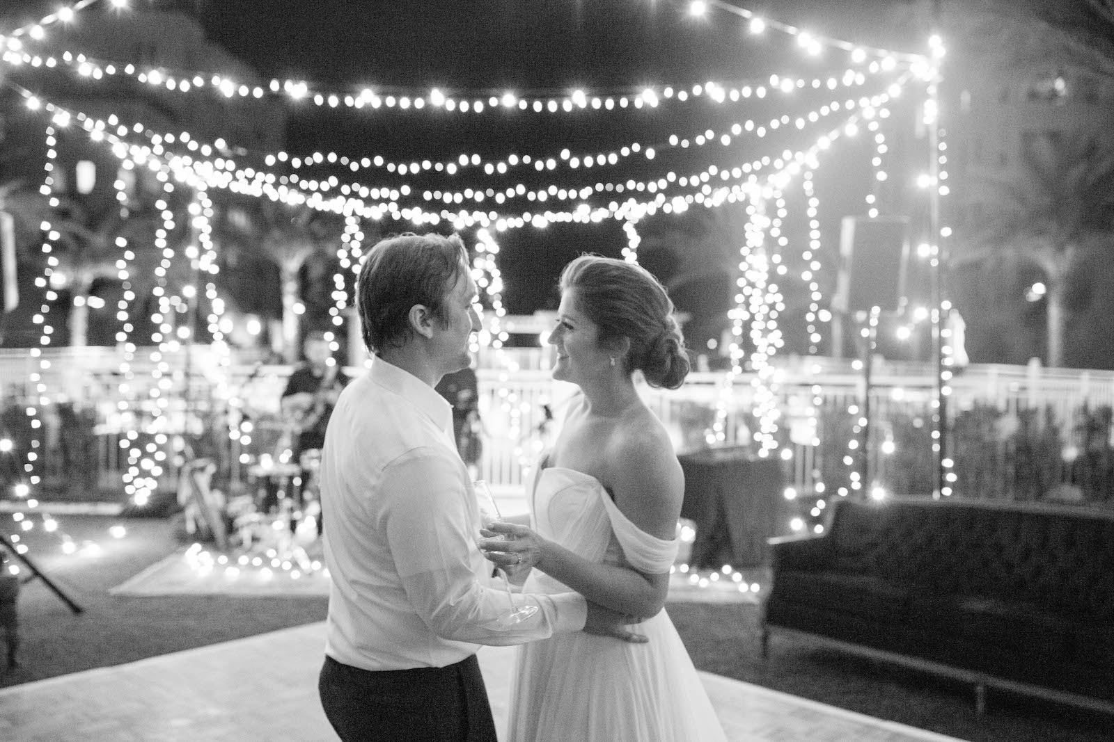 Boho Garden Wedding Reception, Bride and Groom Dancing Under String Lights Black and White Photo