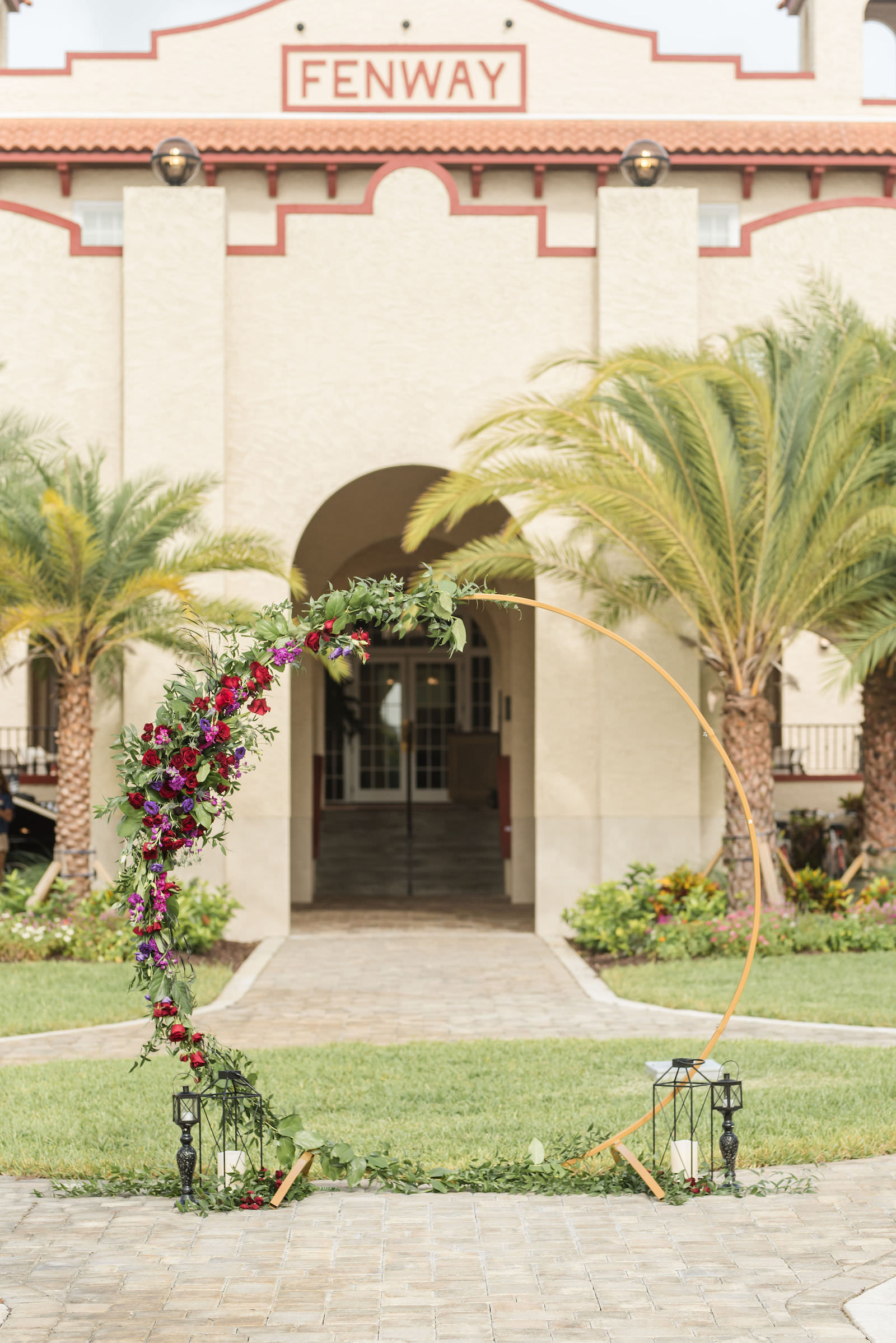 Modern Rock N Roll Wedding, Gold Metal Round Arch with Jewel Tone Red and Purple Flowers with Greenery Floral Arrangements, Acrylic Ghost Chairs | Tampa Bay Wedding Photographer Amanda Zabrocki Photography | Wedding Rentals Kate Ryan Event Rentals | Dunedin Wedding Venue The Fenway