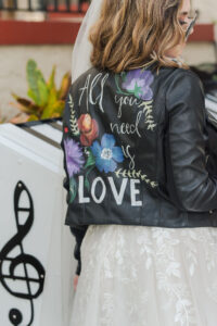 Modern Rock N Roll Bride Wearing Tulle Wedding Dress and Custom Black Leather Jacket With Painted Flowers and "All You Need Is Love Quote" and Sunglasses | Tampa Bay Wedding Photographer Amanda Zabrocki Photography