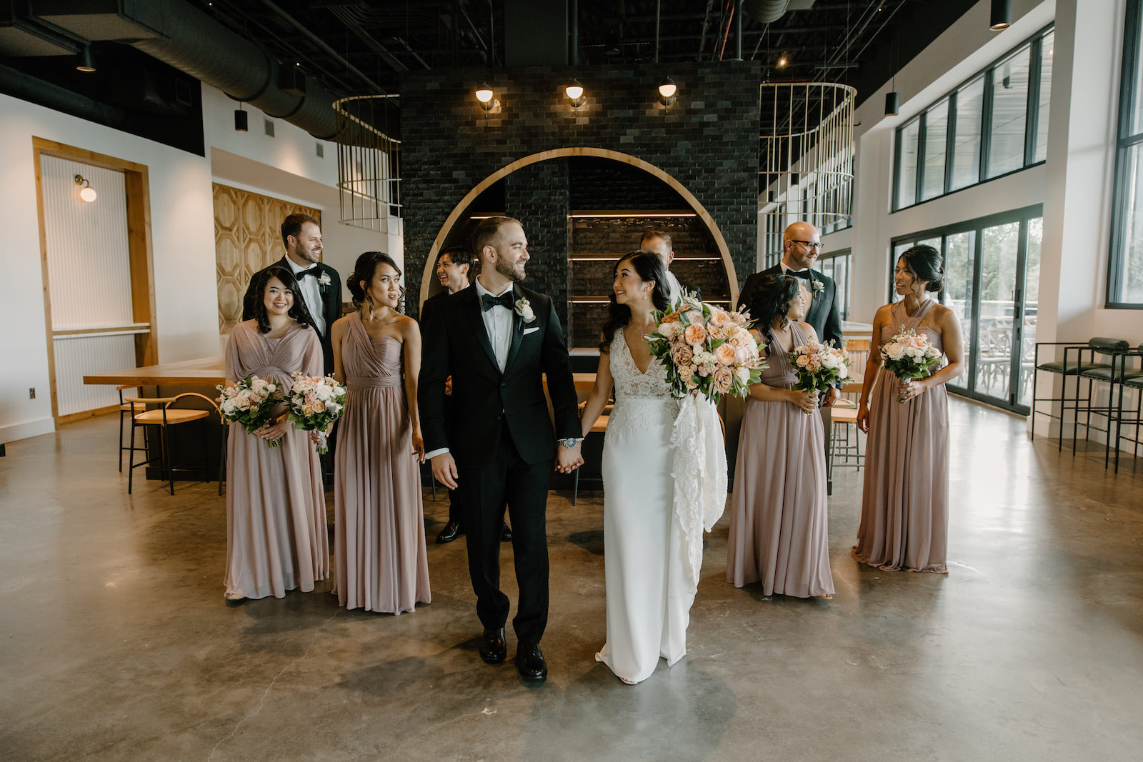Neutral Modern Boho Wedding, Bride in Lace Bodice with Plunging V Neckline Fitted Wedding Dress Holding Lush Blush Pink and Muave Roses with Greenery Floral Bouquet, Groom Wearing Black Tuxedo, Bridesmaids in Mix and Match Mauve Dresses | Unique South Tampa Wedding Venue Hyde House | Tampa Bay Wedding Florist Iza's Flowers | Wedding Hair and Makeup Adore Bridal