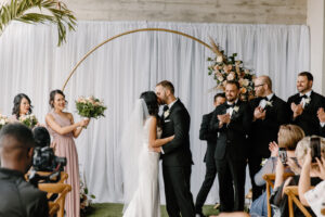 Modern Boho Bride and Groom Exchanging Wedding Vows | Round Gold Metal Arch with Lush Floral Arrangement with Pampas Grass, White Linen Backdrop, Bridesmaids Wearing Mauve Flowy Dresses | Tampa Bay Wedding Florist Iza's Flowers | Wedding Hair and Makeup Adore Bridal | Wedding Venue Hyde House