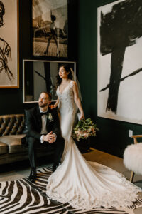 Modern Boho Bride and Groom Sitting on Retro Black Leather Couch at Unique South Tampa Wedding Venue Hyde House