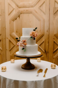 Simple Three Tier White Wedding Cake with Stamped Flower Decor and Burnt Orange Sugar Flowers