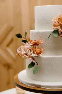 Simple Three Tier White Wedding Cake with Stamped Flower Decor and Burnt Orange Sugar Flowers
