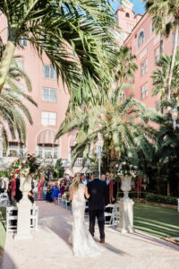Elegant Navy Wedding, Bride and Groom Exchanging Wedding Vows in Courtyard of Historic Pink Palace St. Pete Wedding Venue The Don Cesar | Wedding Florist Botanica | Wedding Planner Perfecting the Plan