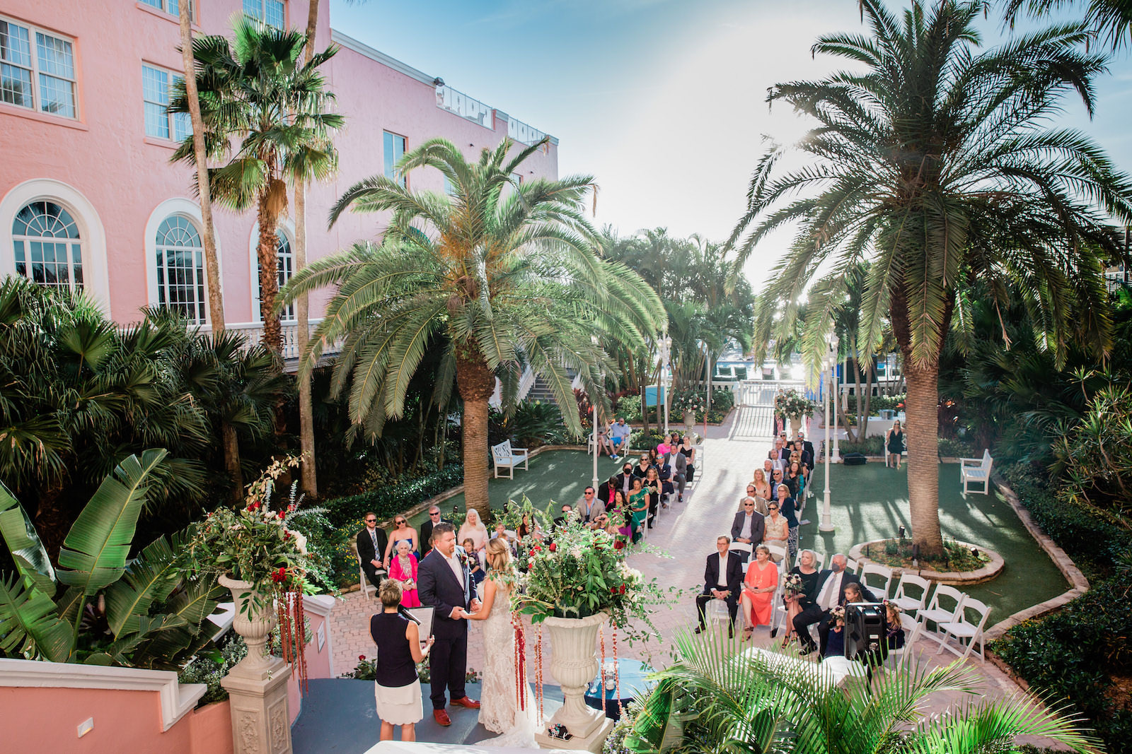 Elegant Navy Wedding, Bride and Groom Exchanging Wedding Vows in Courtyard of Historic Pink Palace St. Pete Wedding Venue The Don Cesar | Wedding Florist Botanica | Wedding Planner Perfecting the Plan